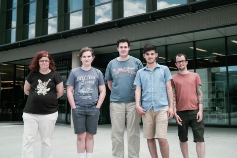 vier junge Männer und eine Frau stehen vor Styria Center Gebäude.