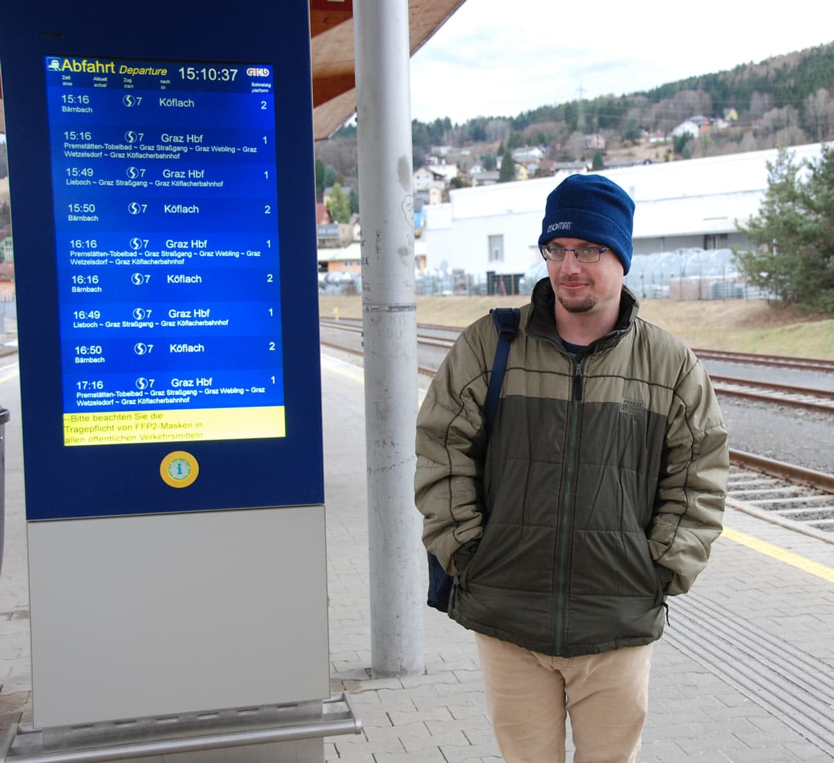 junger Mann mit Behinderung steht am Bahnsteig, um selbstbestimmt mit dem Zug zu reisen