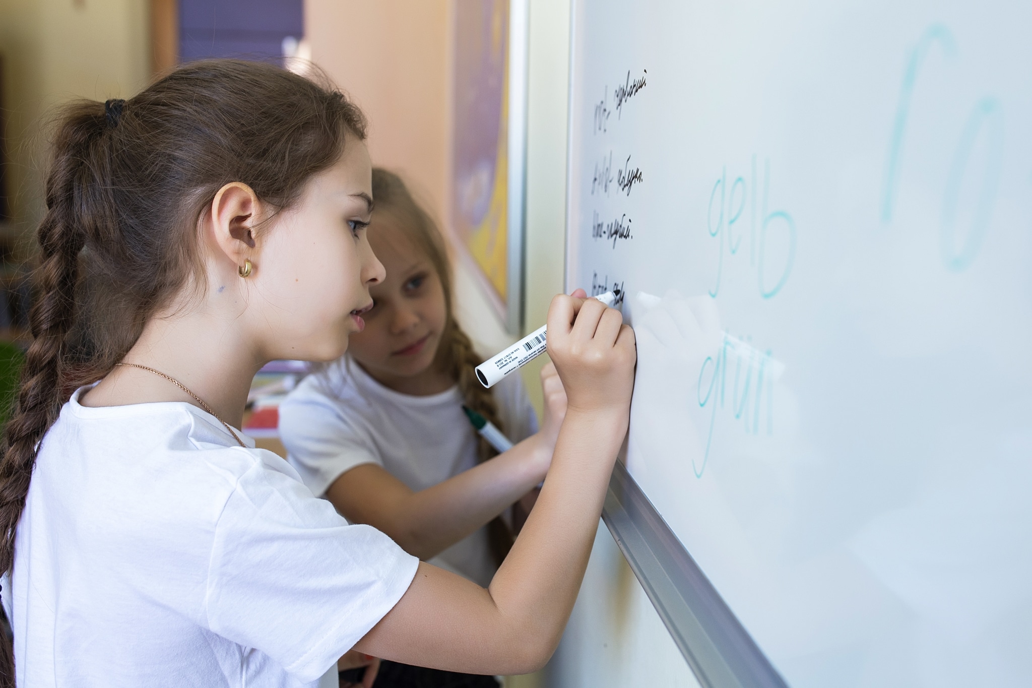 2 ukrainische Mädchen schreiben deutsche Wörter an die Schultafel