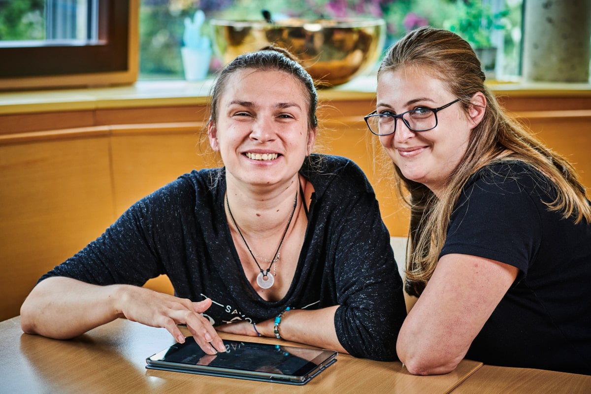 zwei junge Frauen sitzen am Tisch und lernen mit IPad zu arbeiten