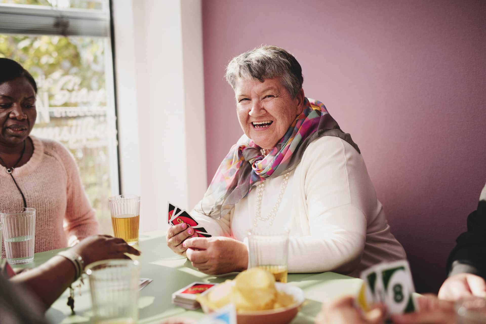 Ältere Dame beim Kartenspielen in Wohnraum von Lebensgroß