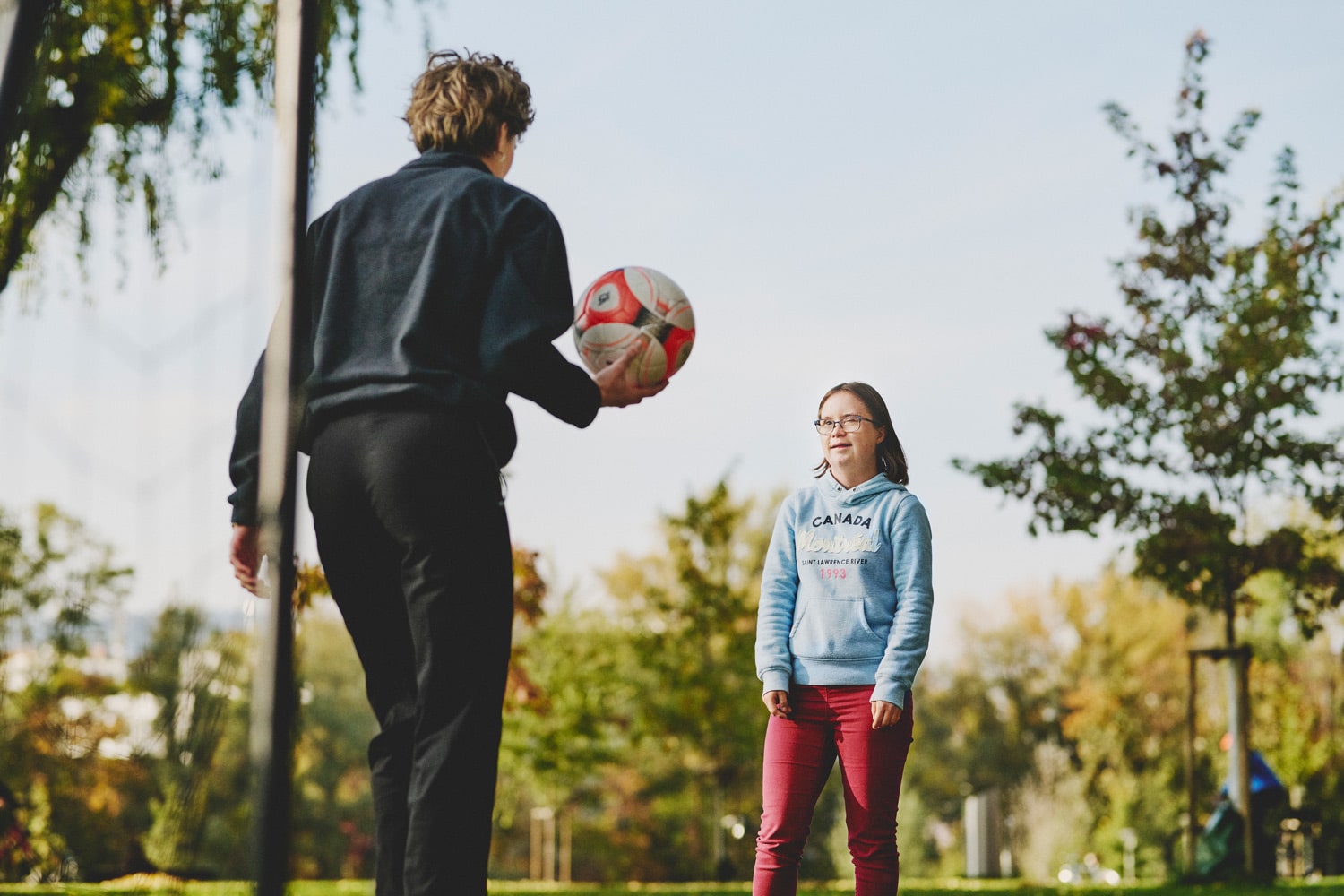 Trainerin spielt mit Mädchen mit Downsyndrom Fußball