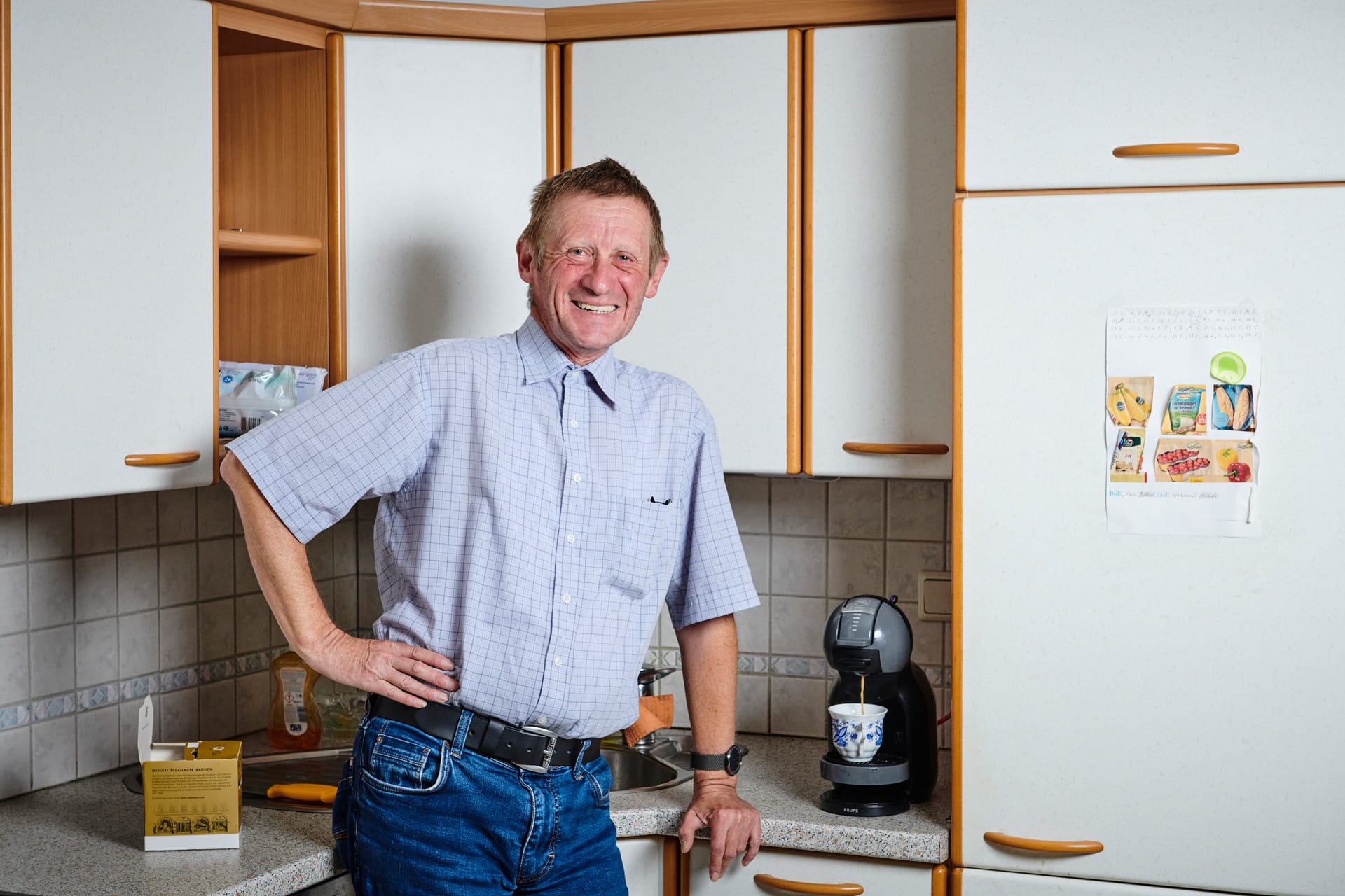 Mann steht vor Küchenblock in seiner eigene Wohnung und wird von der LebensGroß Mobilen Wohnassistenz begleitet