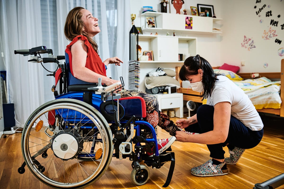 Junge Frau im Rollstuhl mit ihrer Betreuerin in individuell gestaltetem Zimmer