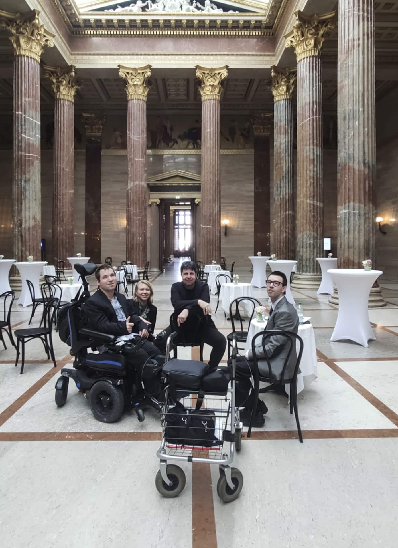 zwei Männer im Rollstuhl und ein Mann und eine Frau sitzend im österreichischen Parlament