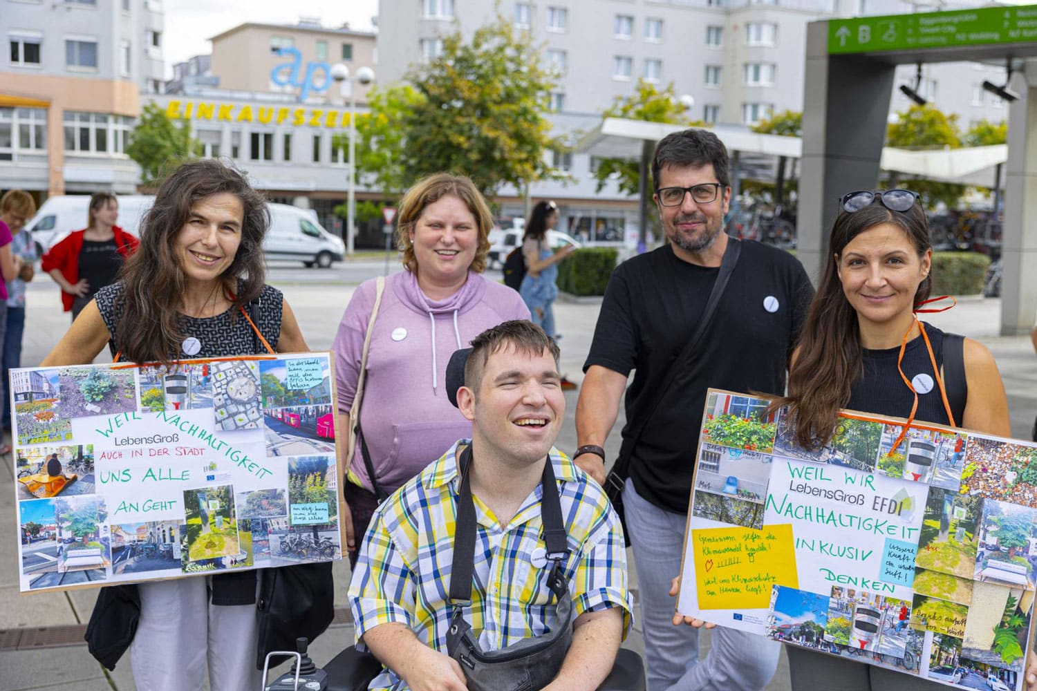 drei Frauen und zwei Männer, einer davon im Rollstuhl mit Plakaten für Nachhaltigkeit bei Klimastreik in den Händen