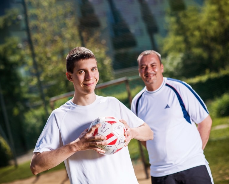 Junger Mann mit Fußball in der Hand stehend vor seinem Trainer