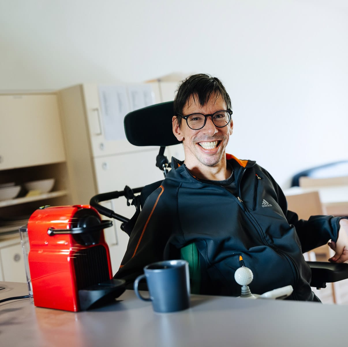 Mann im Rollstuhl mit seiner roten Kaffeemaschine in der LebensGroß Kurzzeitbegleitung