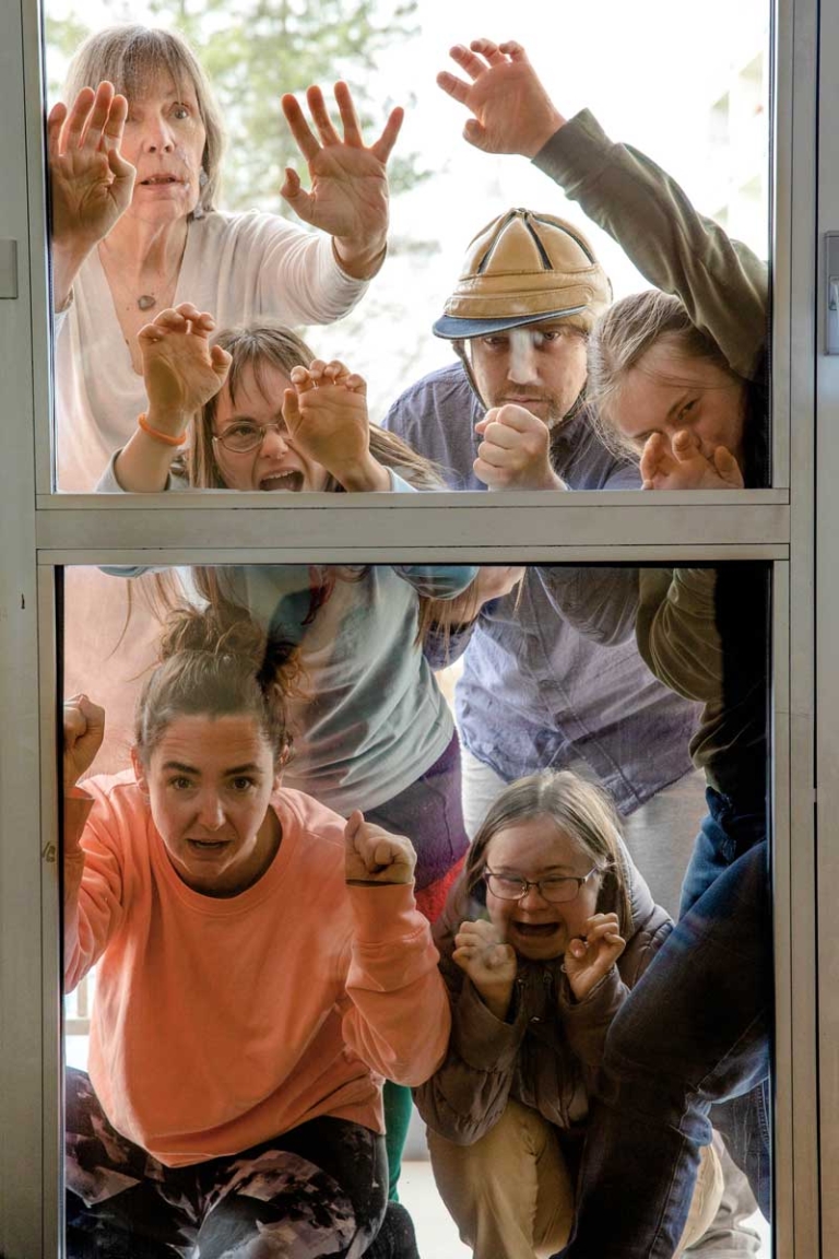 Fünf Frauen und ein Mann, alle Teilnehmer:innen der Theaterakademie von LebensGroß, schauen durch ein Fenster.
